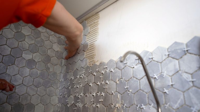Construction,Worker,Installs,Modern,Hexagonal,Tiles,On,A,Bathroom,Wall,